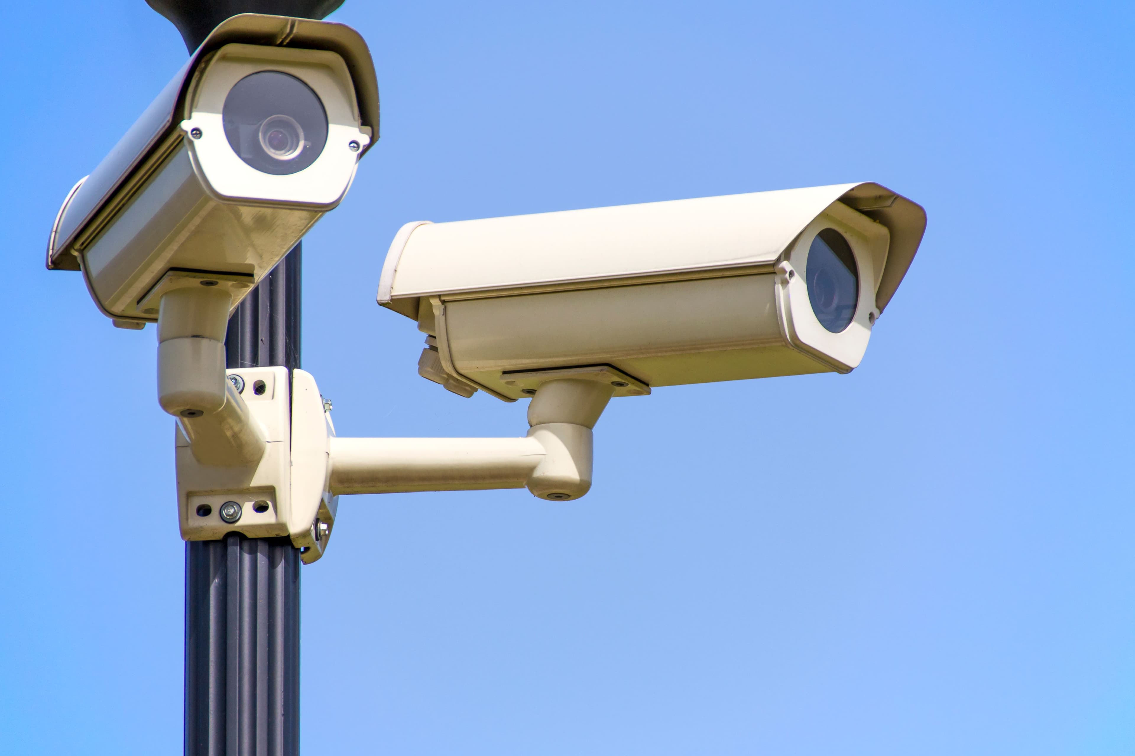 Outdoor CCTV camera mounted on a post against a blue sky